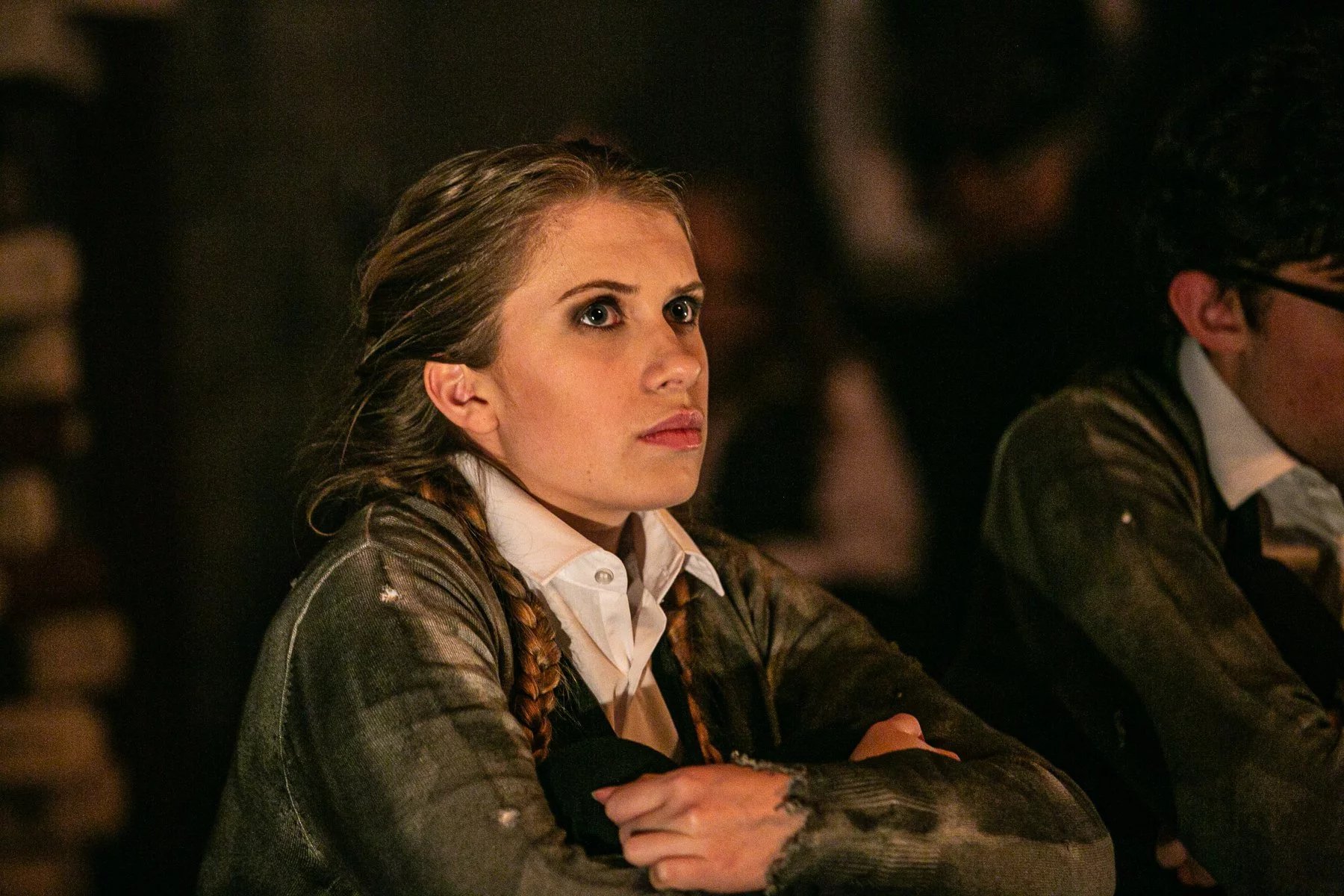 Billie-Jo as Gretel in Grimm's tales. She is sat on the floor with her arms crossed looking sad. She is wearing a dirty grey cardigan.