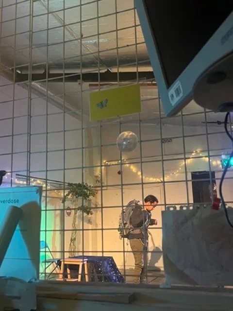 A stage photo of an actor with a backpack onstage. 